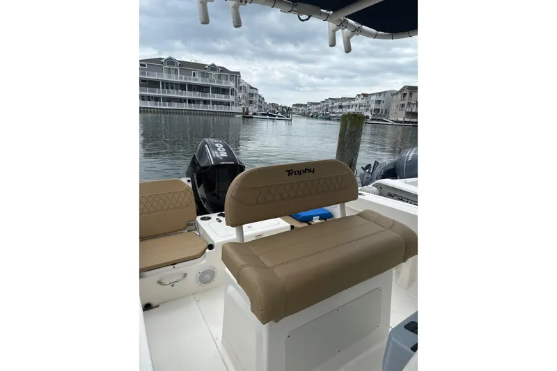 Slide: The Image of 2024 Trophy CC22 boat interior with tan seating, docked near waterfront homes. - 4