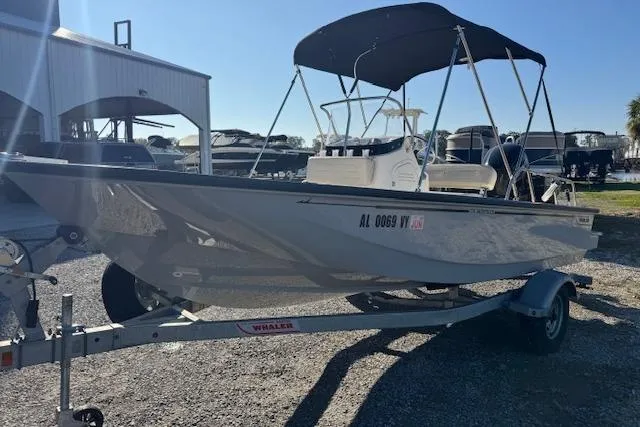 Slide: The Image of 2023 Boston Whaler 170 Montauk boat on trailer with canopy, parked outdoors. - 11