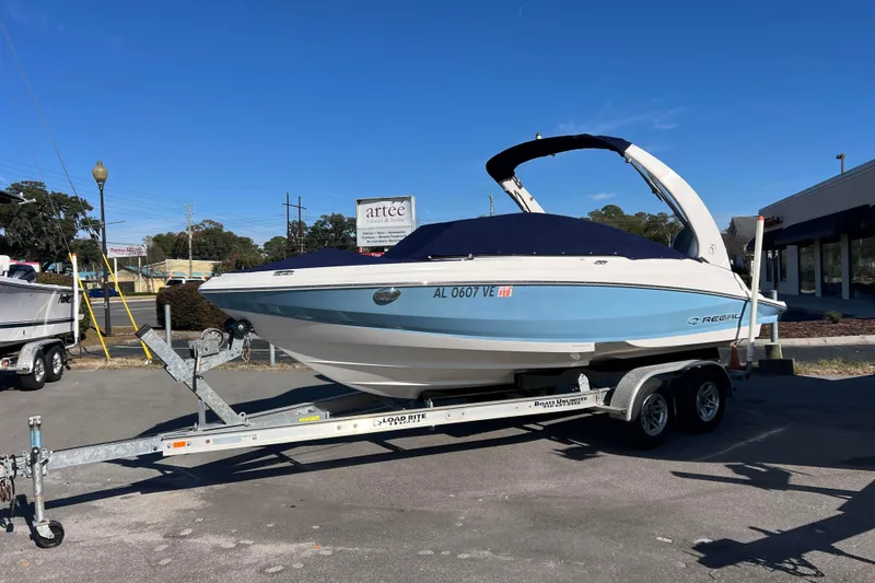 Slide: The Image of 2020 Regal 21 OBX boat on trailer, parked outdoors under clear blue sky. - 1