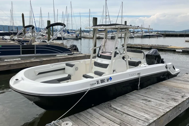 Slide: The Image of 2024 Trophy CC22 boat docked at marina with sailboats in background. - 2