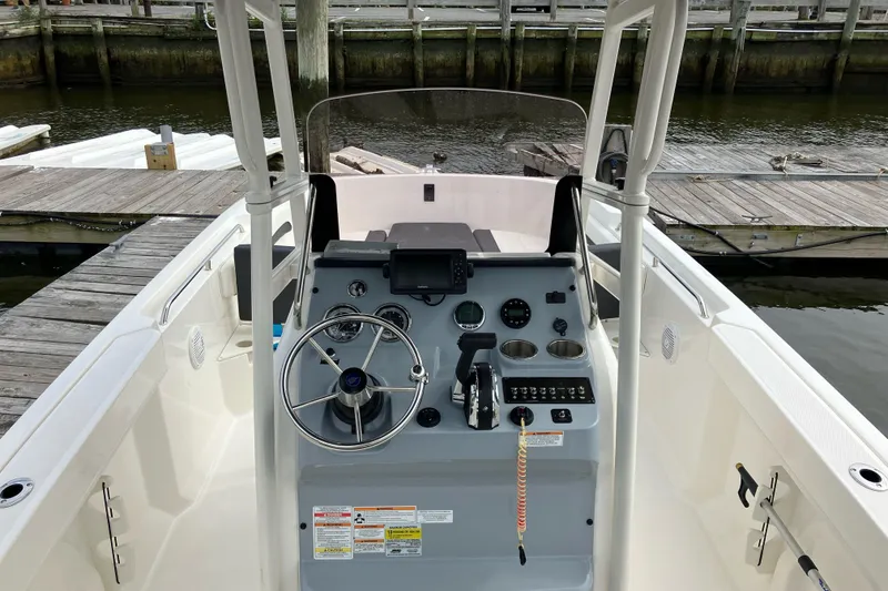 Slide: The Image of 2024 Trophy CC22 boat dashboard with steering wheel and controls at a dock. - 4