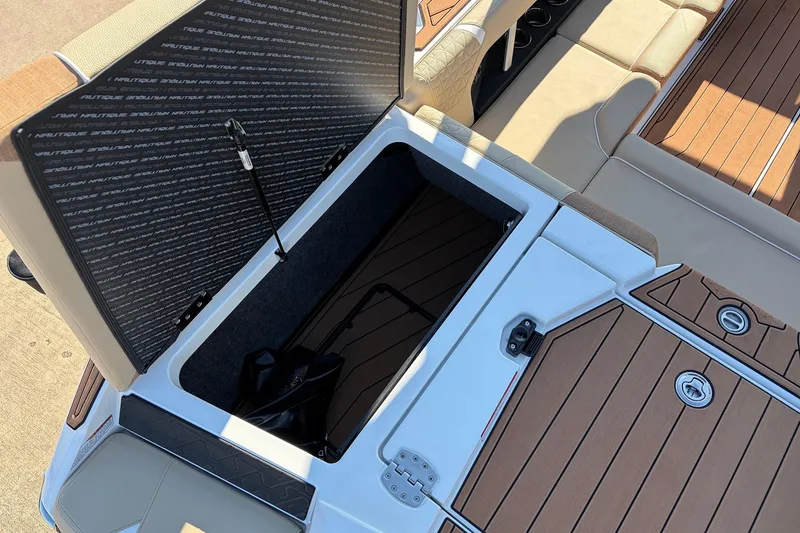 Slide: The Image of 2026 Nautique Super Air Nautique GS22 storage compartment with open hatch and cushioned seating. - 57