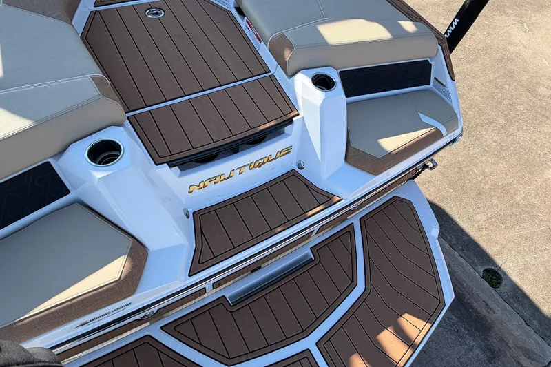 Slide: The Image of 2026 Nautique Super Air Nautique GS22 boat deck with cushioned seating and cup holders. - 67