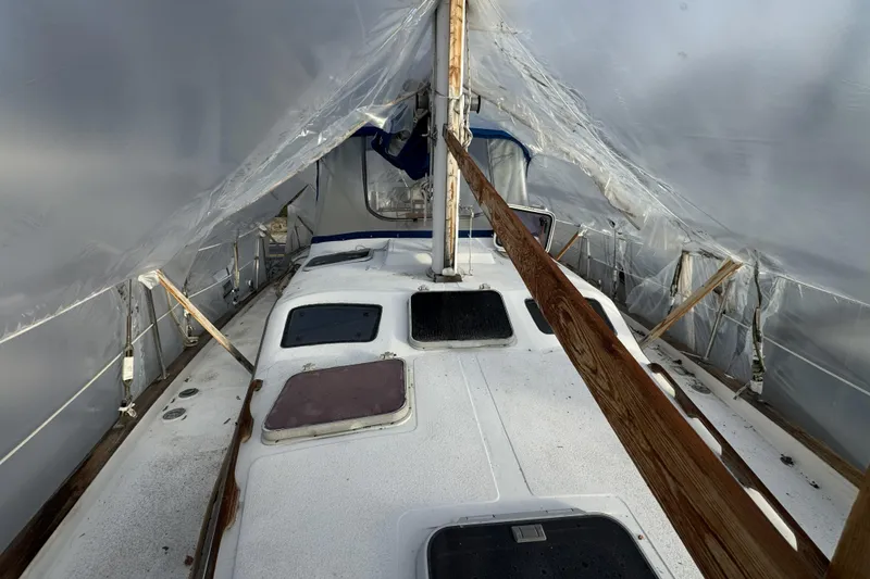 Slide: The Image of 1987 Irwin 38 sailboat under protective cover, showing deck and hatches. - 11