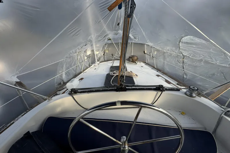 Slide: The Image of 1987 Irwin 38 sailboat cockpit under protective cover, showcasing steering wheel and deck. - 12