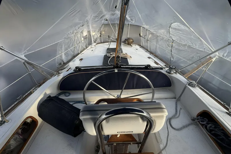 Slide: The Image of 1987 Irwin 38 sailboat cockpit under protective cover, featuring steering wheel and seating. - 13