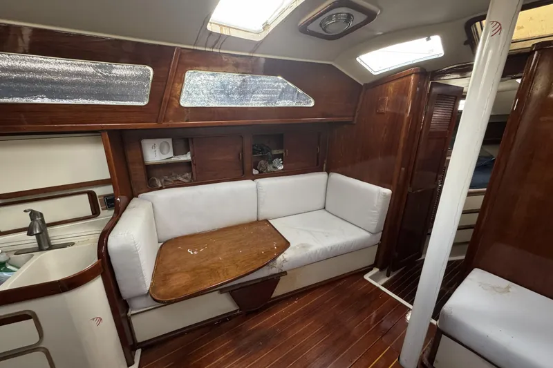 Slide: The Image of 1987 Irwin 38 yacht interior with wooden finish, white seating, and compact kitchen area. - 17