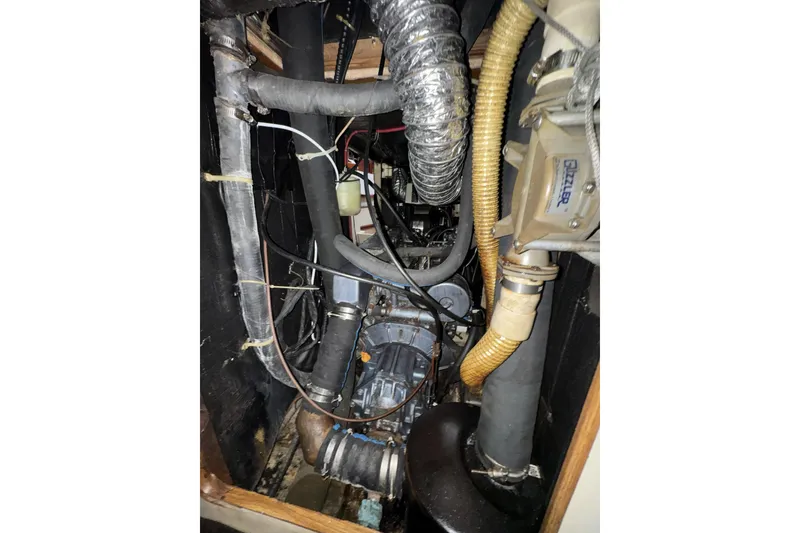 Slide: The Image of Engine compartment of a 1987 Irwin 38 sailboat, featuring various hoses and mechanical components. - 33
