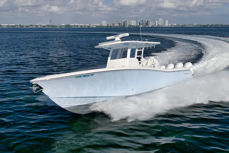 Slide: The Image of 2022 Invincible 39 Open Fisherman boat cruising on open water with city skyline backdrop. - 4