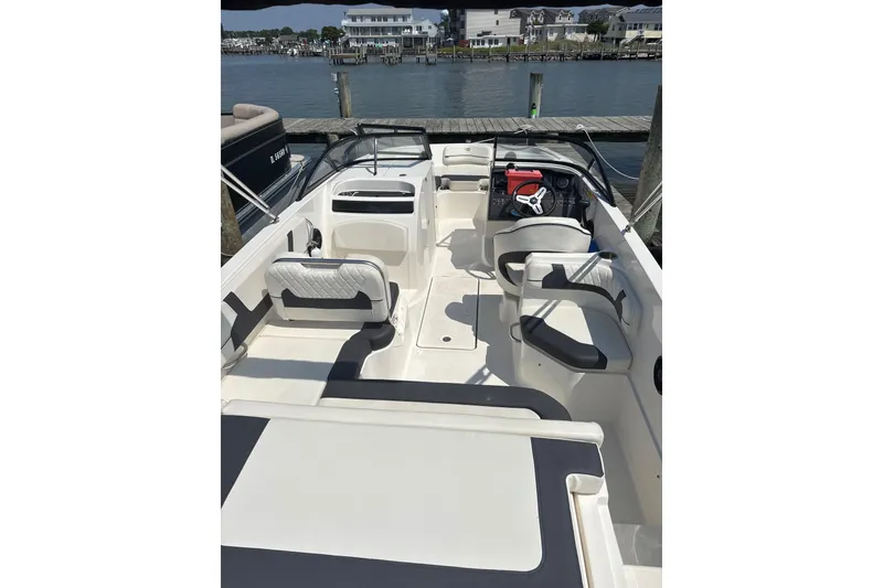 Slide: The Image of 2024 Bayliner VR6 Bowrider OB interior with seating and steering wheel, docked by the water. - 5