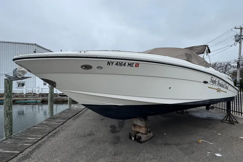Slide: The Image of 2007 Sea Ray 270 SLX boat on dry dock, white hull, covered, near marina. - 5