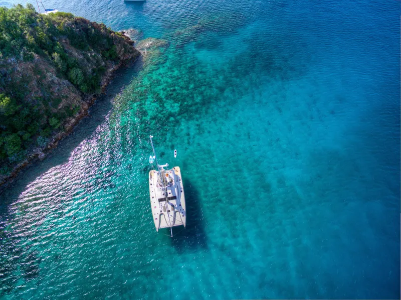 Slide: The Image of Aerial view of a 2010 Privilege 745 yacht anchored near a rocky coastline in clear blue water. - 6
