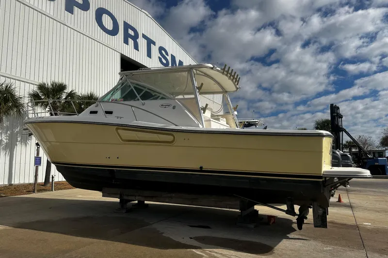 Slide: The Image of 2003 Rampage 38 Express boat on display outside a large building under a cloudy sky. - 3