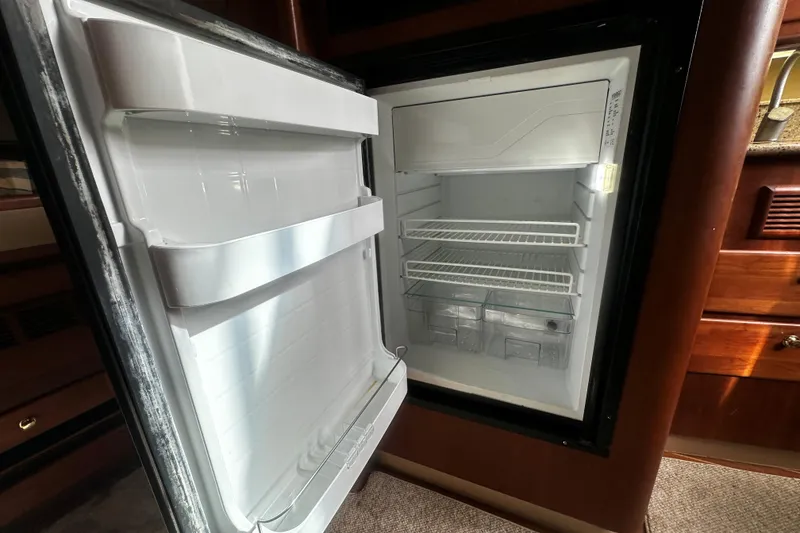Slide: The Image of Open refrigerator inside 2003 Rampage 38 Express boat, showing shelves and storage compartments. - 7