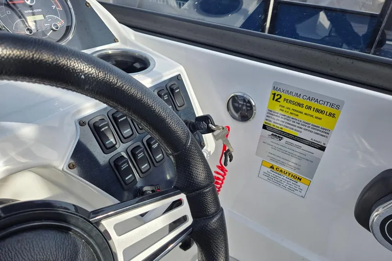 Slide: The Image of 2024 Godfrey Hurricane 235SD boat dashboard with capacity label and steering wheel. - 13