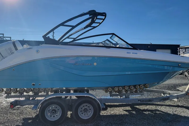 Slide: The Image of 2024 Godfrey Hurricane 235SD boat on trailer, blue and white design, sunny day. - 2