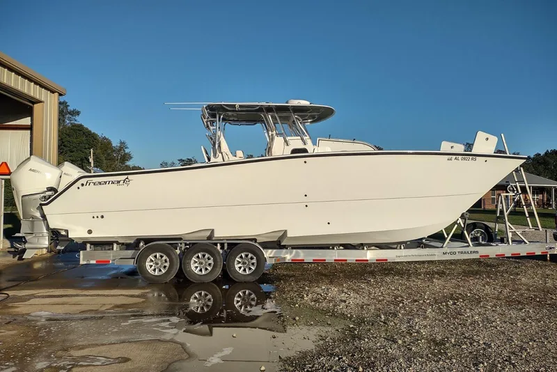 Slide: The Image of 2022 Freeman 34 boat on trailer, parked outdoors under clear blue sky. - 4
