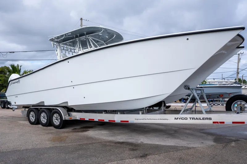 Slide: The Image of 2022 Freeman 34 boat on Myco trailer, parked outdoors under cloudy sky. - 5