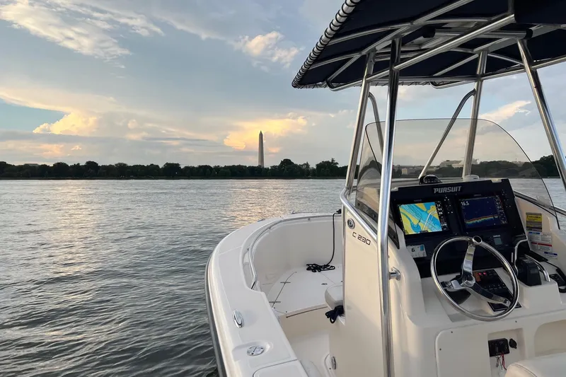 Slide: The Image of 2012 Pursuit C 230 Center Console boat on calm water with scenic view. - 17