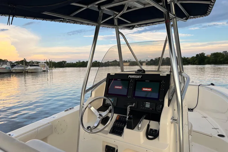 Slide: The Image of 2012 Pursuit C 230 Center Console boat on calm water at sunset. - 18