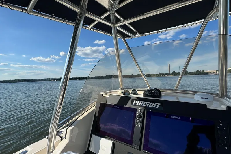 Slide: The Image of 2012 Pursuit C 230 Center Console boat on a sunny lake, featuring Simrad navigation system. - 7