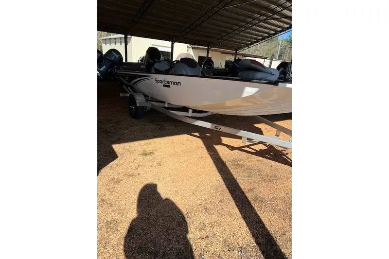 The Image of 2025 G3 Sportsman 1710 boat under a metal canopy, parked on gravel. - 1