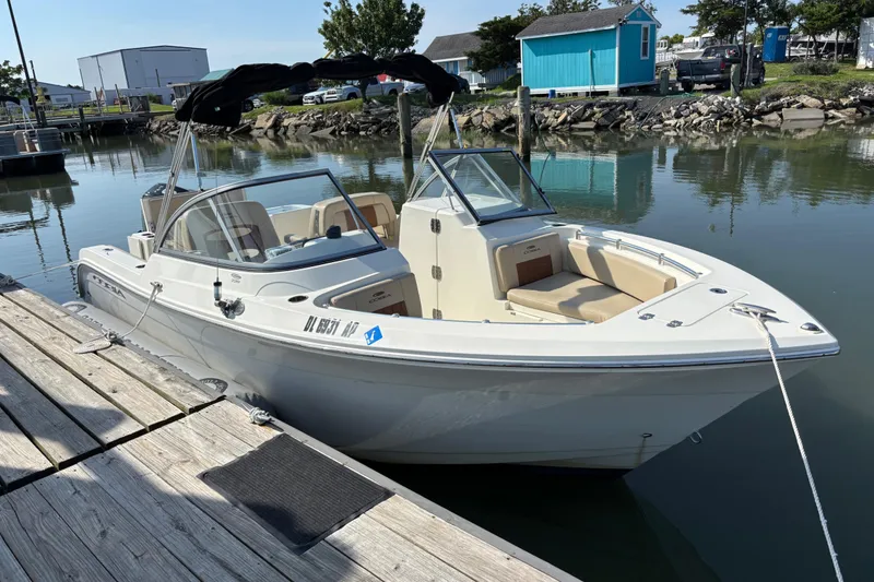 The Image of 2024 Cobia 220 Dual Console boat docked in a serene marina setting. - 1