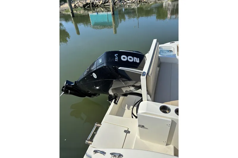 Slide: The Image of 2024 Cobia 220 Dual Console boat with powerful V6 outboard motor on calm water. - 10