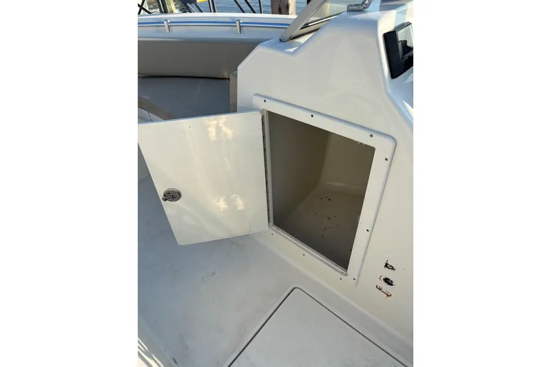 Slide: The Image of 2024 Cobia 220 Dual Console boat storage compartment with open door. - 7