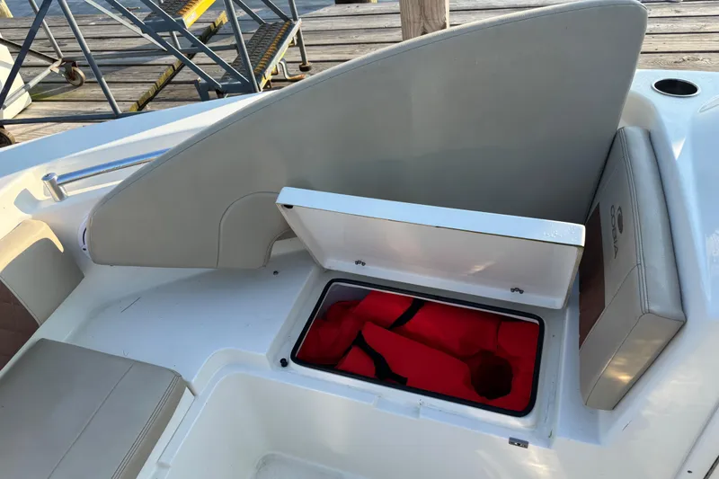 Slide: The Image of 2024 Cobia 220 Dual Console boat with open storage compartment and red life jacket. - 8