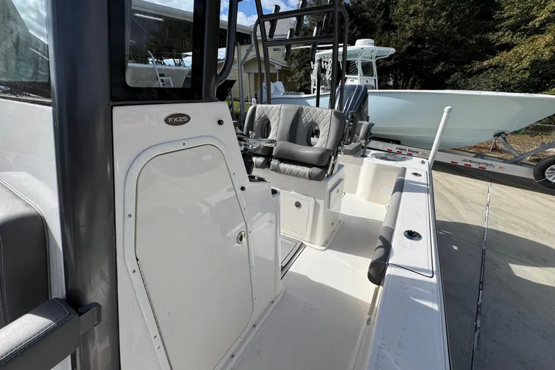 Slide: The Image of 2026 Sea Born FX261 Bay boat interior with seating and console, parked outdoors. - 24