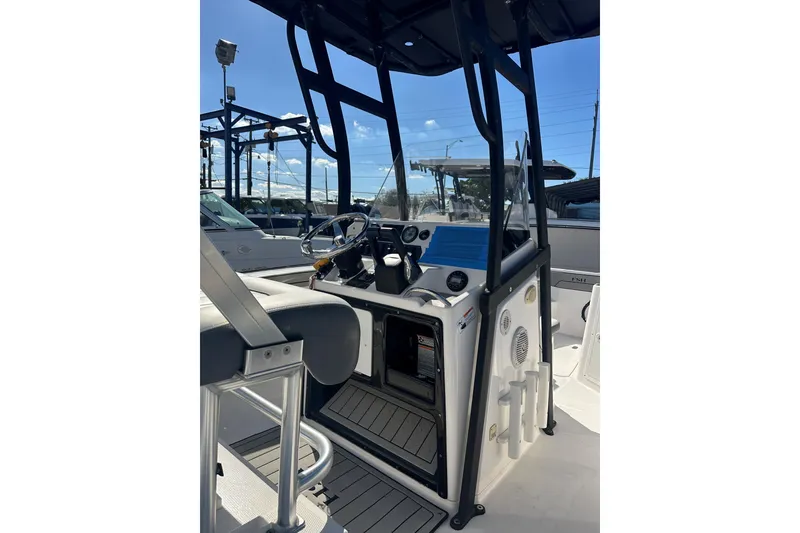 Slide: The Image of 2020 Yamaha Boats 210 FSH interior with steering console and seating, under clear blue sky. - 13