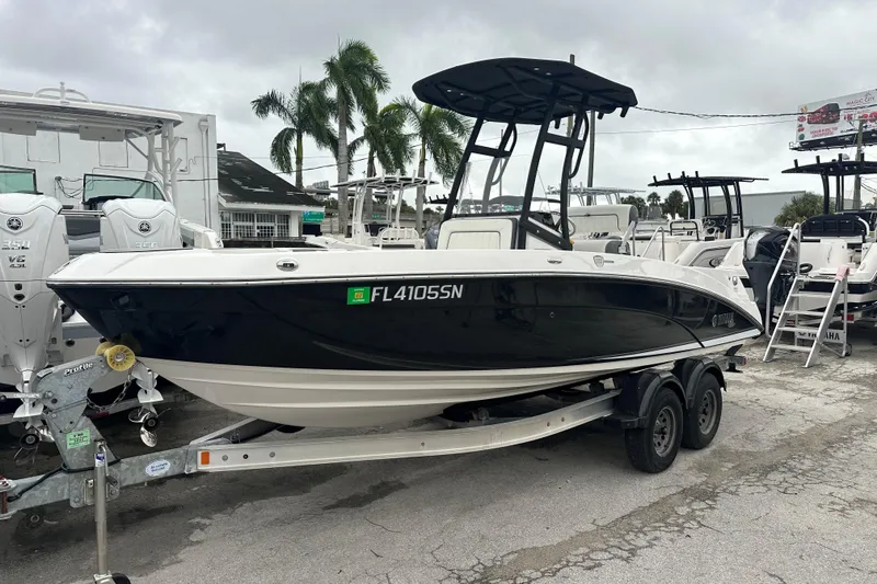 Slide: The Image of 2020 Yamaha Boats 210 FSH on trailer, parked at a marina with palm trees. - 3