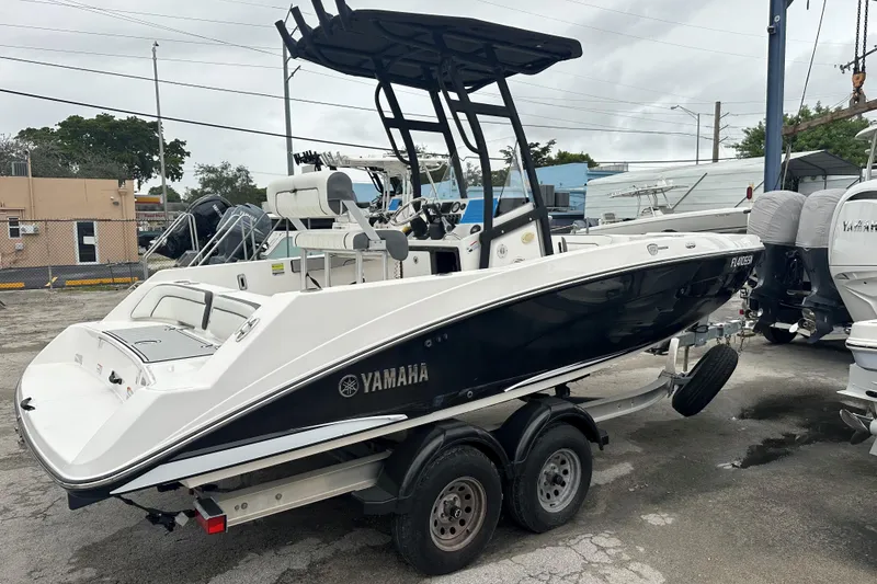Slide: The Image of 2020 Yamaha Boats 210 FSH on trailer, parked outdoors, showcasing sleek design and modern features. - 5