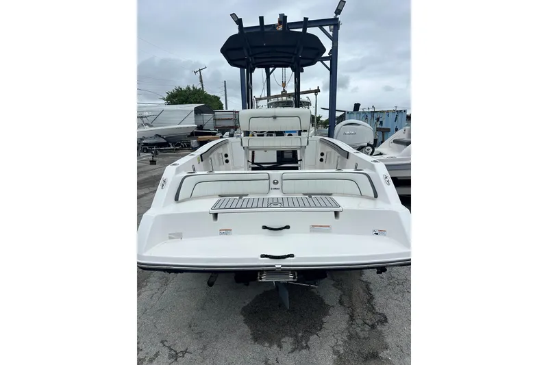 Slide: The Image of 2020 Yamaha Boats 210 FSH, rear view, white exterior, parked on concrete. - 6