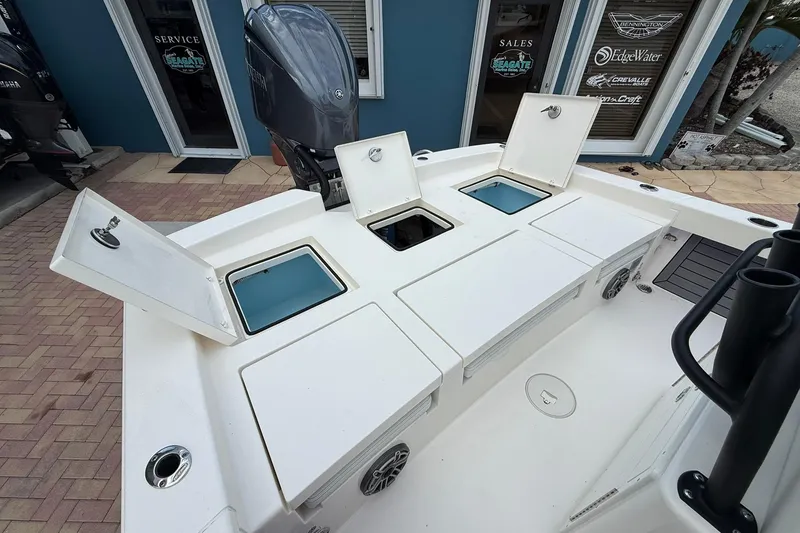 Slide: The Image of 2023 Pathfinder 2600 TRS boat with open storage compartments and motor, displayed outdoors. - 16