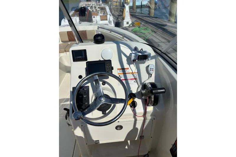 Slide: The Image of 2024 Cobia 220 Dual Console boat helm with steering wheel and controls. - 4