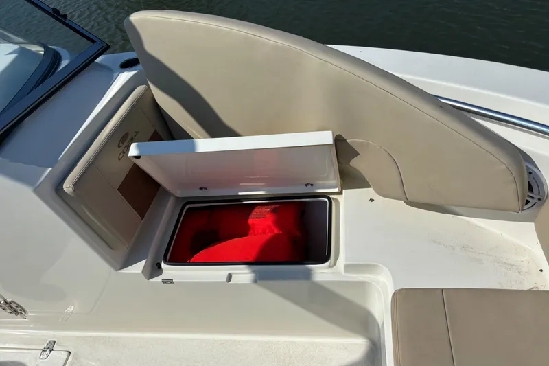 Slide: The Image of 2024 Cobia 220 Dual Console boat seat storage with red life jackets. - 5