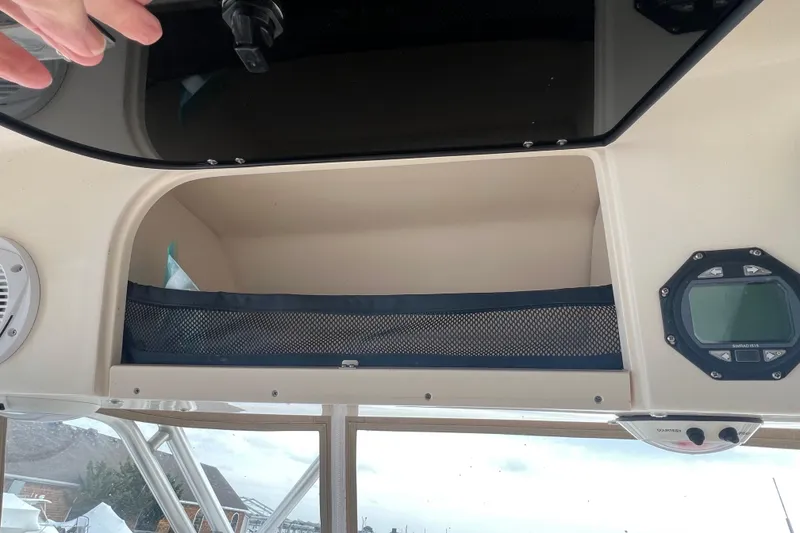 Slide: The Image of Storage compartment on a 2006 Grady-White Express 330 boat with mesh netting and control panel. - 13