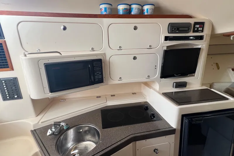 Slide: The Image of 2006 Grady-White Express 330 galley with microwave, sink, stove, and storage cabinets. - 16