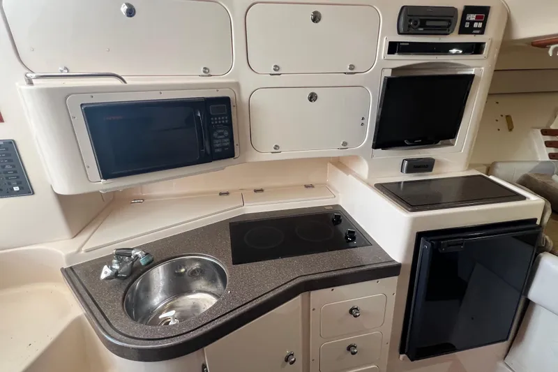 Slide: The Image of 2006 Grady-White Express 330 boat kitchen with microwave, sink, stove, and fridge. - 17