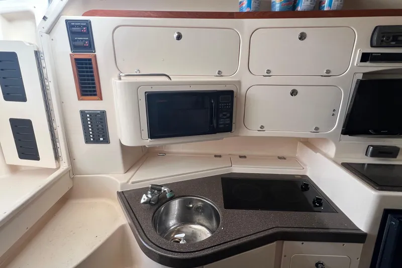 Slide: The Image of 2006 Grady-White Express 330 boat kitchen with sink, microwave, and storage cabinets. - 18