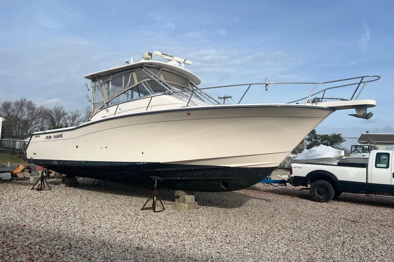 Slide: The Image of 2006 Grady-White Express 330 boat on dry land, parked beside a truck. - 2