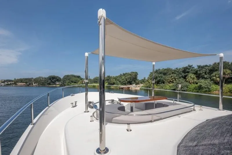 Slide: The Image of 2017 Ocean Alexander Motor Yacht deck with seating and sunshade, near lush shoreline. - 64