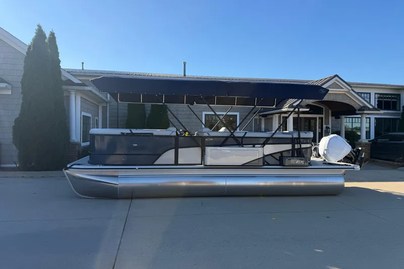 Slide: The Image of 2026 Crest Conquest 230 L pontoon boat with cover, parked outdoors on a sunny day. - 4