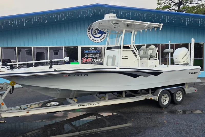 The Image of 2019 Ranger 2510 Bay Ranger boat on trailer outside a blue building. - 0