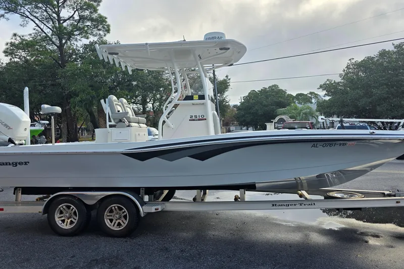 Slide: The Image of 2019 Ranger 2510 Bay Ranger boat on trailer outside marina, with tractor nearby. - 3