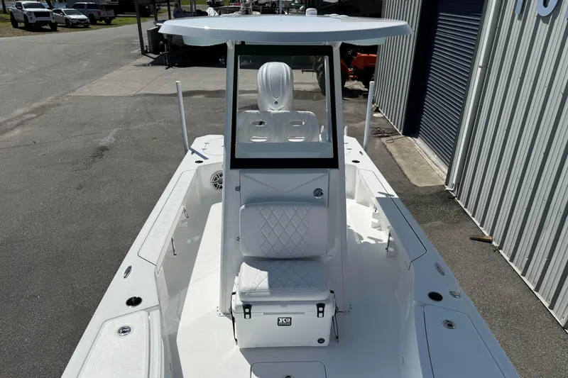 Slide: The Image of 2026 Blazer 2550 GTS boat with T-top and seating, docked near a metal building. - 32