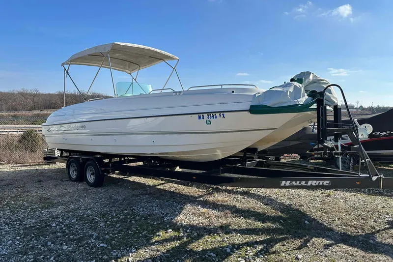 The Image of 1998 Bayliner 2659 Rendezvous boat on trailer, parked outdoors under clear sky. - 0