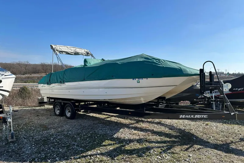 Slide: The Image of 1998 Bayliner 2659 Rendezvous boat on trailer, covered with green tarp, outdoors. - 14